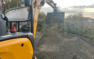 Mini pelle compacte en action sur un chantier, pelletant un tas de gravier