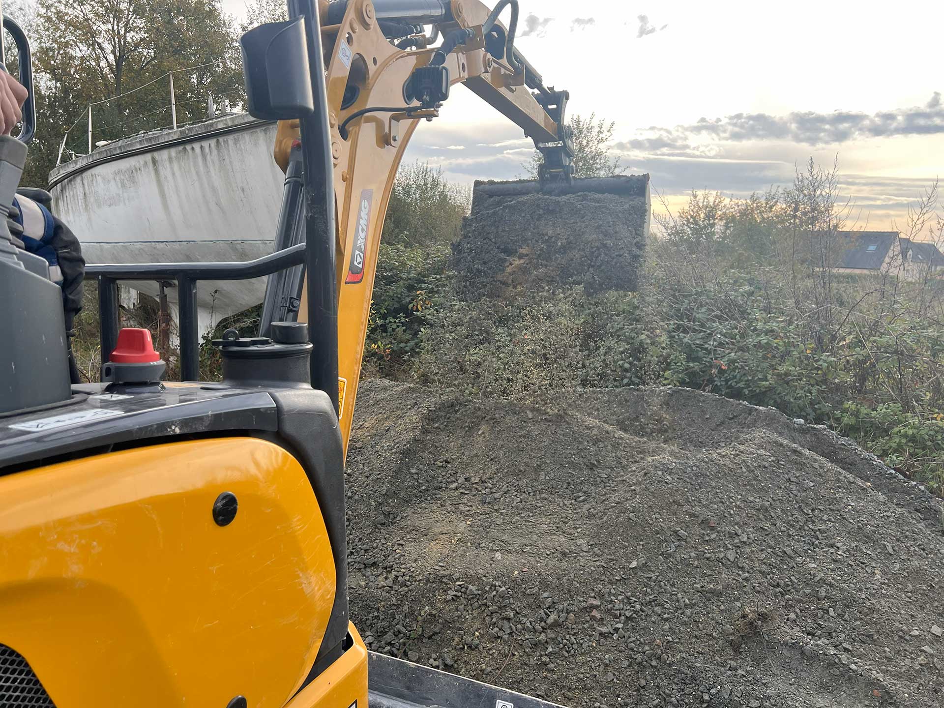 Mini pelle compacte en action sur un chantier, pelletant un tas de gravier